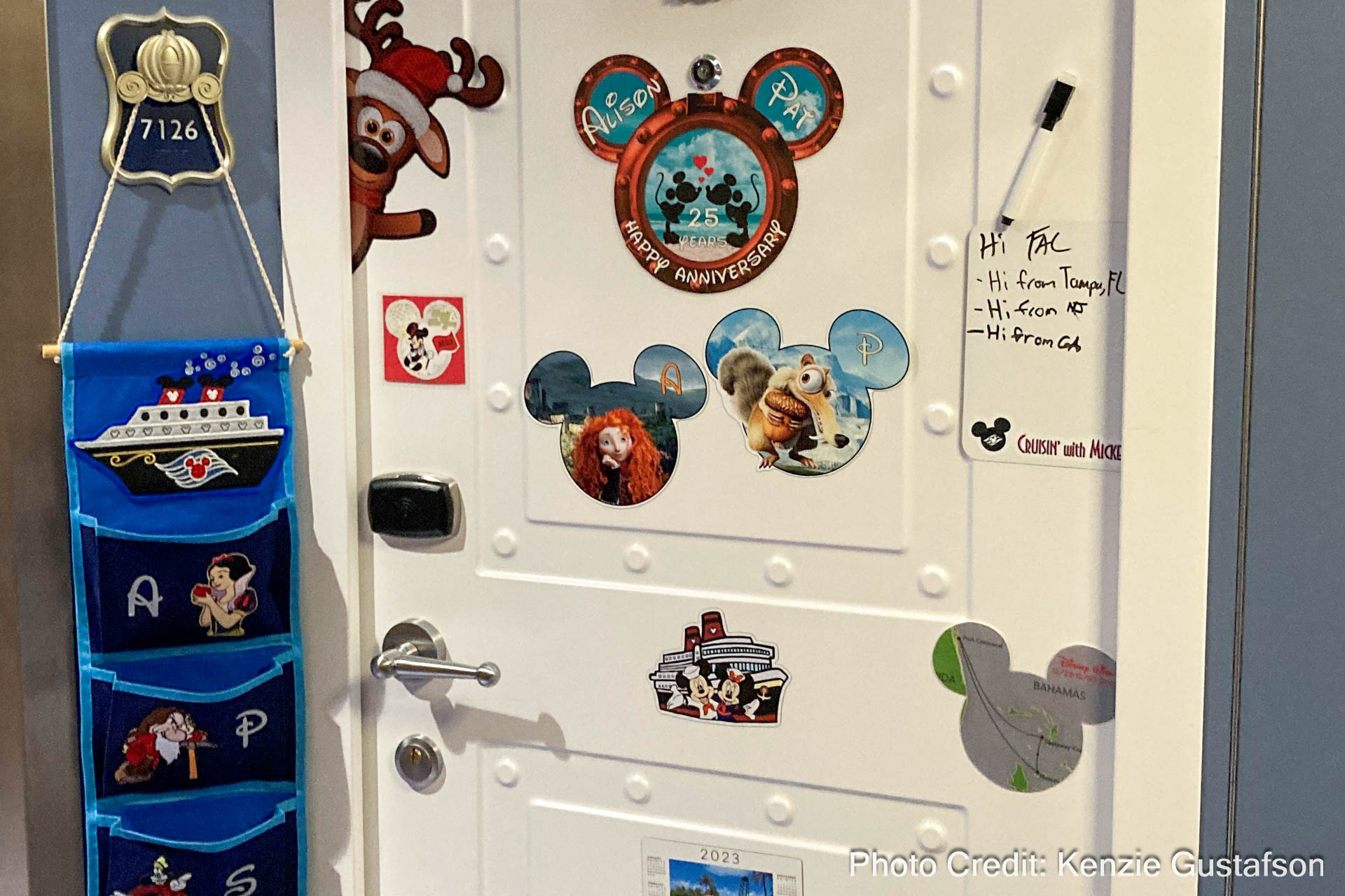 Disney Cruise Line stateroom door decorated with mickey icon magnets and a blue fish extender with black pockets