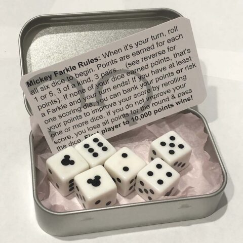 Six dice in a tin with game instructions. The "one's dice" features a Mickey icon instead of the normal dot.