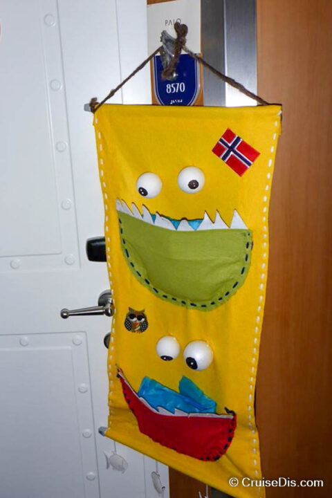 Yellow, homemade fish extender with two monsters with googly eyes. The mouths of monsters act as the pockets of the fish extender. There is a Norwegian Flag at the top.