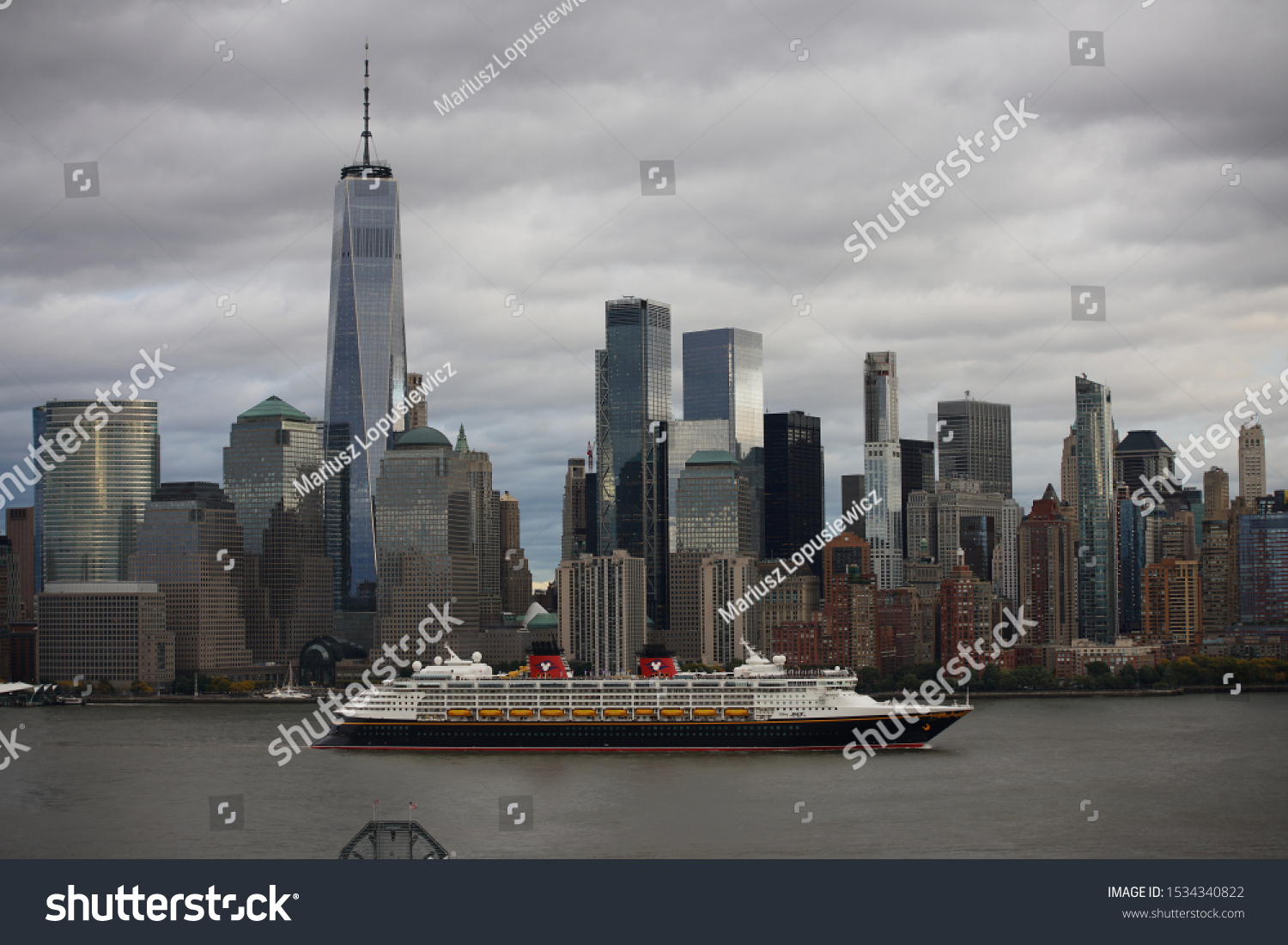 Disney Cruise ship sailing down the Hudson with the New York City skyline in the background.