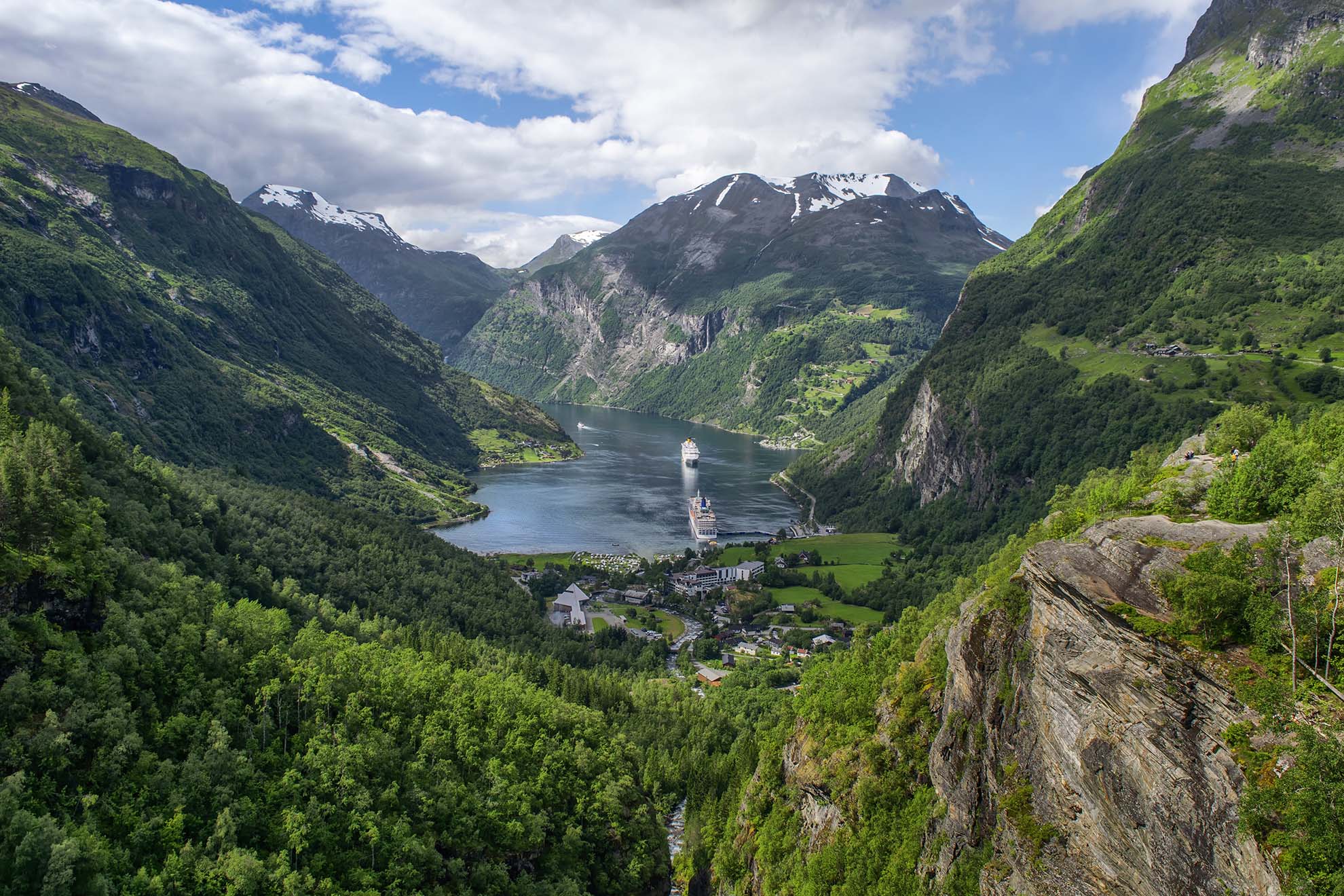 Two cruise ships in the the waters of the green Norwegian Fjords.