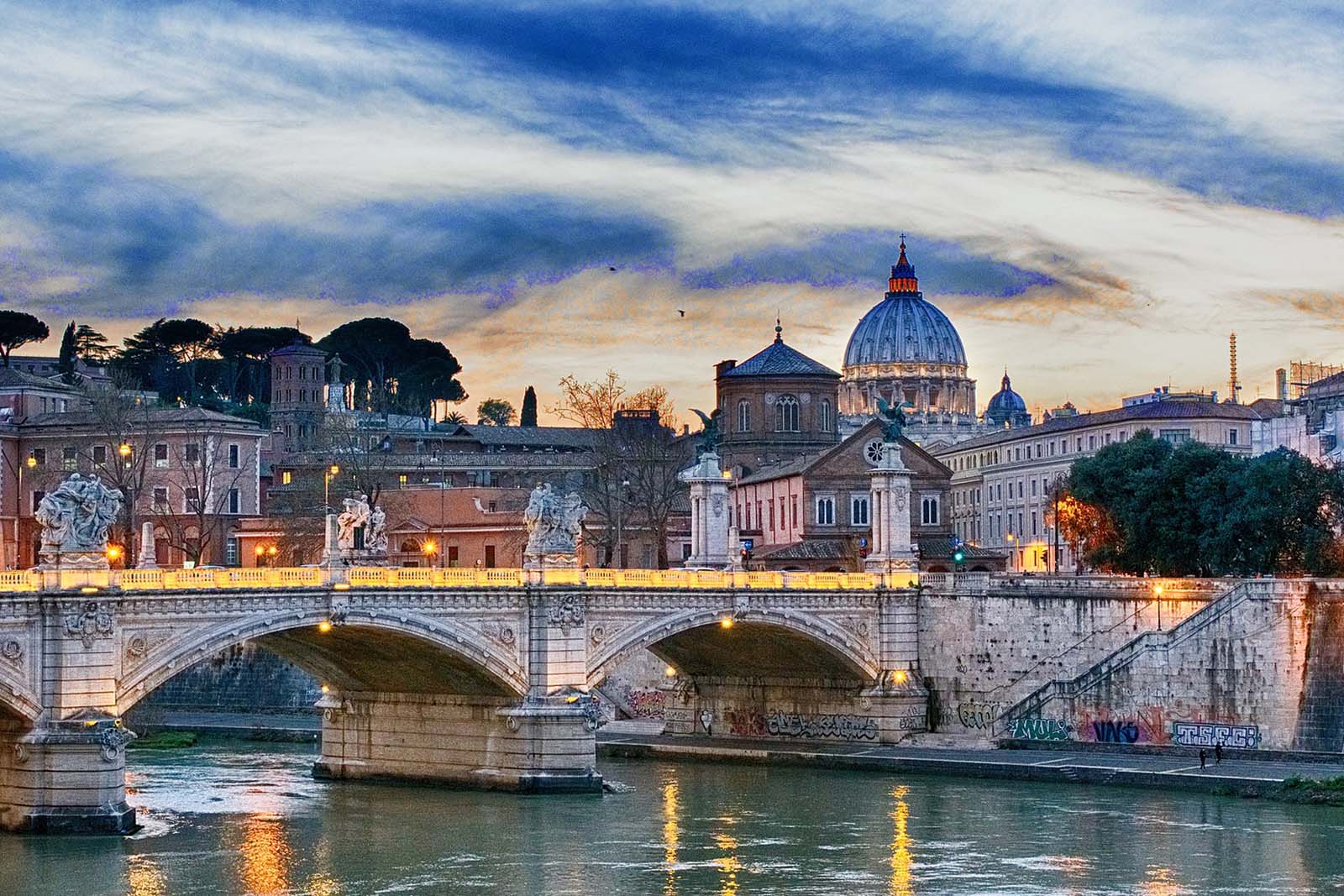 River Tiber in Rome at sunset with St. Peter's Basilica in the background.